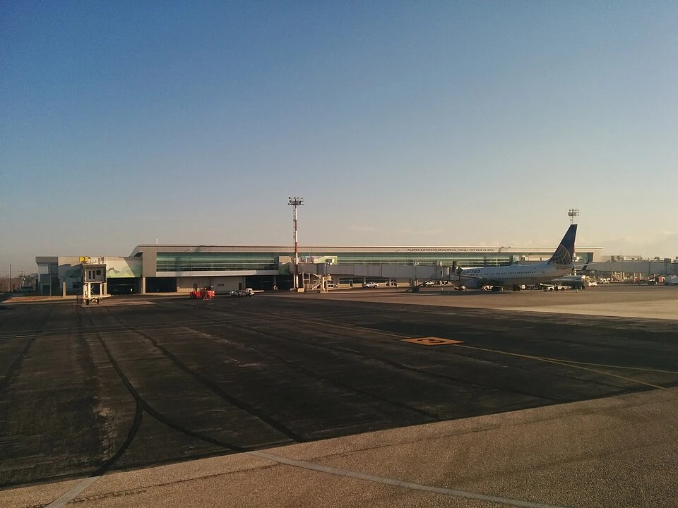 The low terminal building at Liberia's Guanacaste Airport seen across the apron, with an airliner parked at a gate.